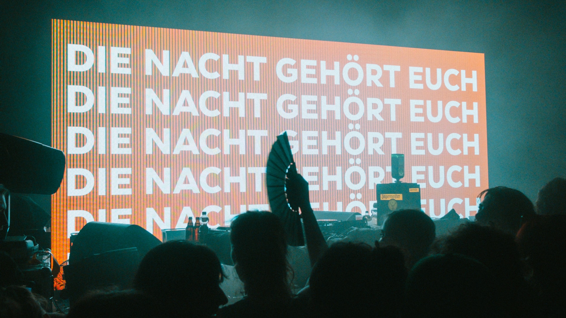 Schriftzug: Die Nacht Gehört Euch mit feiernden Personen